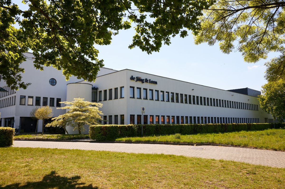 Wit pand omringt door groene bomen en struiken is het pand van de Jong & Laan vestiging Enschede