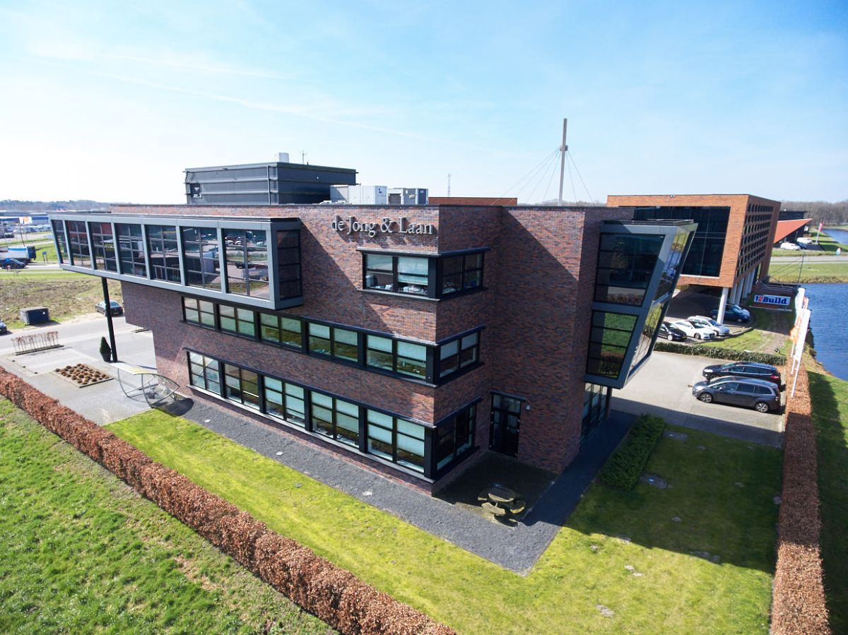 Bruin gebouw van de Jong en Laan omringd door een grasveld is vestiging Nijverdal